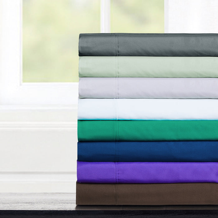 Stack of folded bed sheets in various colors on a white background