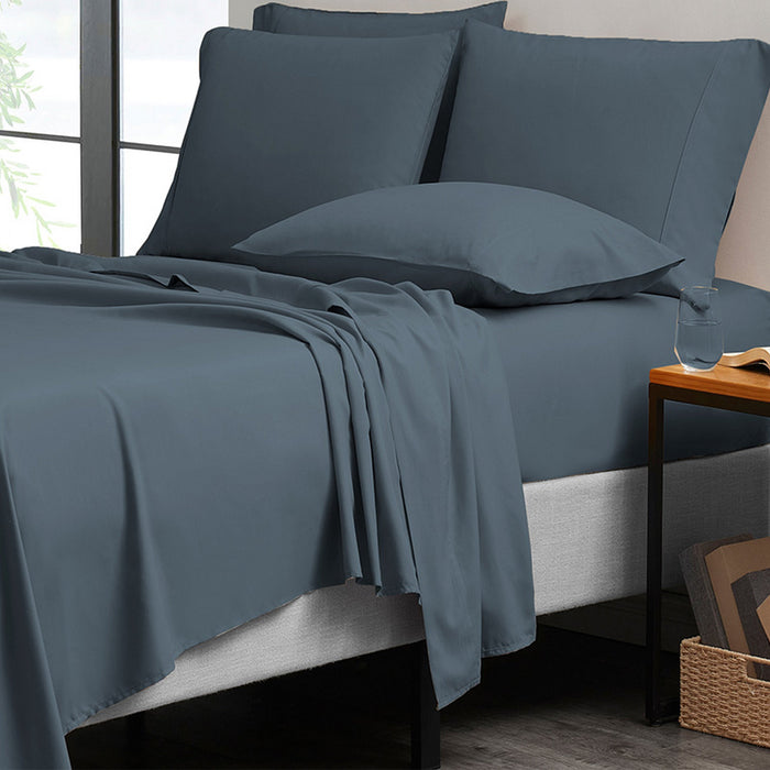 Blue bedding set on a bed with pillows and a side table.