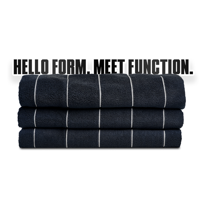 Stack of folded dark blue towels with white stripes on a white background, featuring the text 'HELLO FORM. MEET FUNCTION.'
