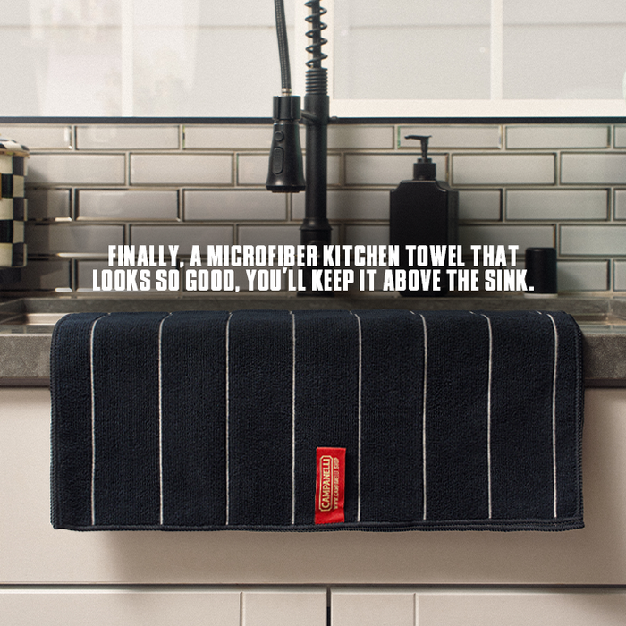 Dark microfiber kitchen towel with a red label on a kitchen counter.