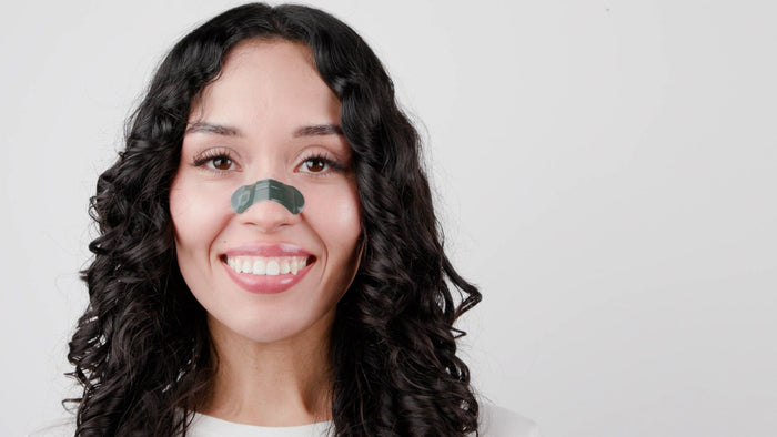 Woman with a sleep mask on her face against a plain background
