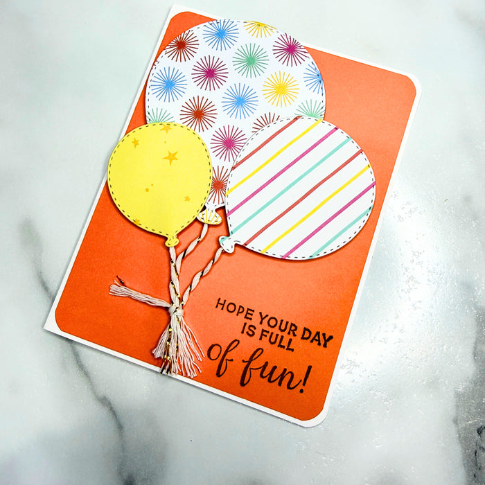 Greeting card with colorful balloons and text saying "hope your day is full of fun!" on an orange background